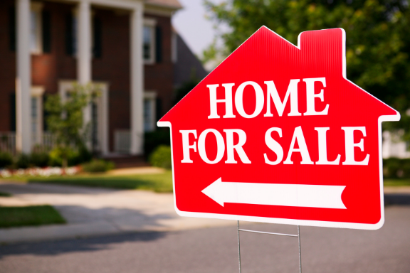 Close up of a sign that reads “home for sale”