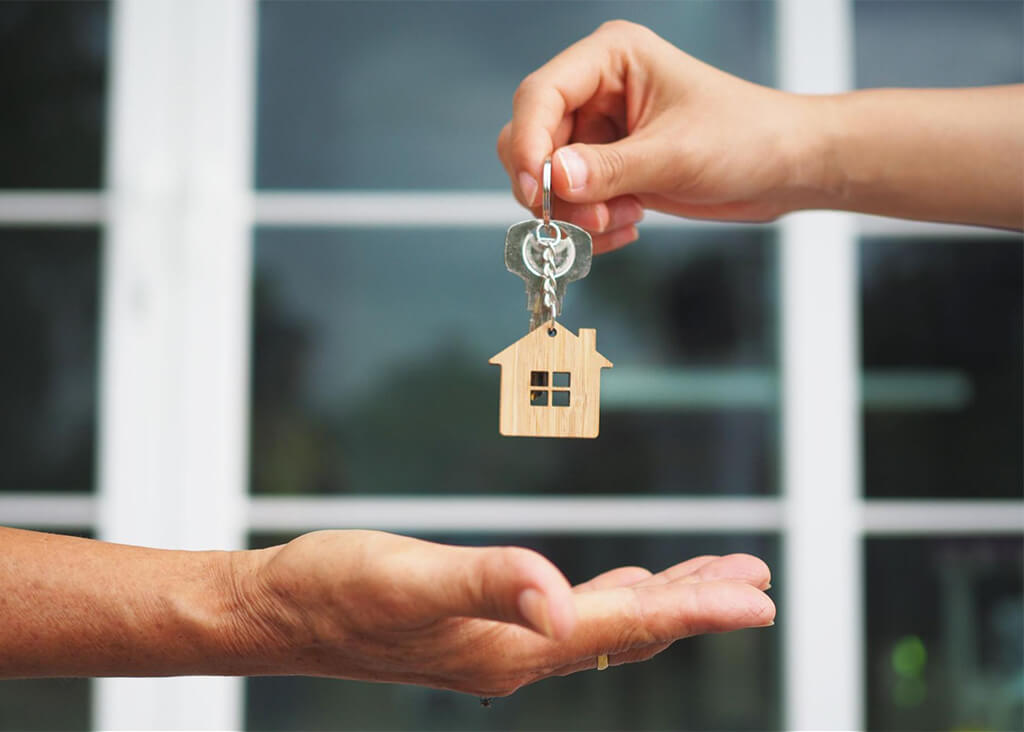 Close-up of a hand giving the keys to a sold house with new windows