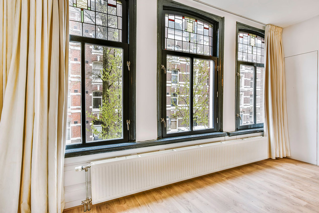 Three black windows and a radiator in an apartment unit 