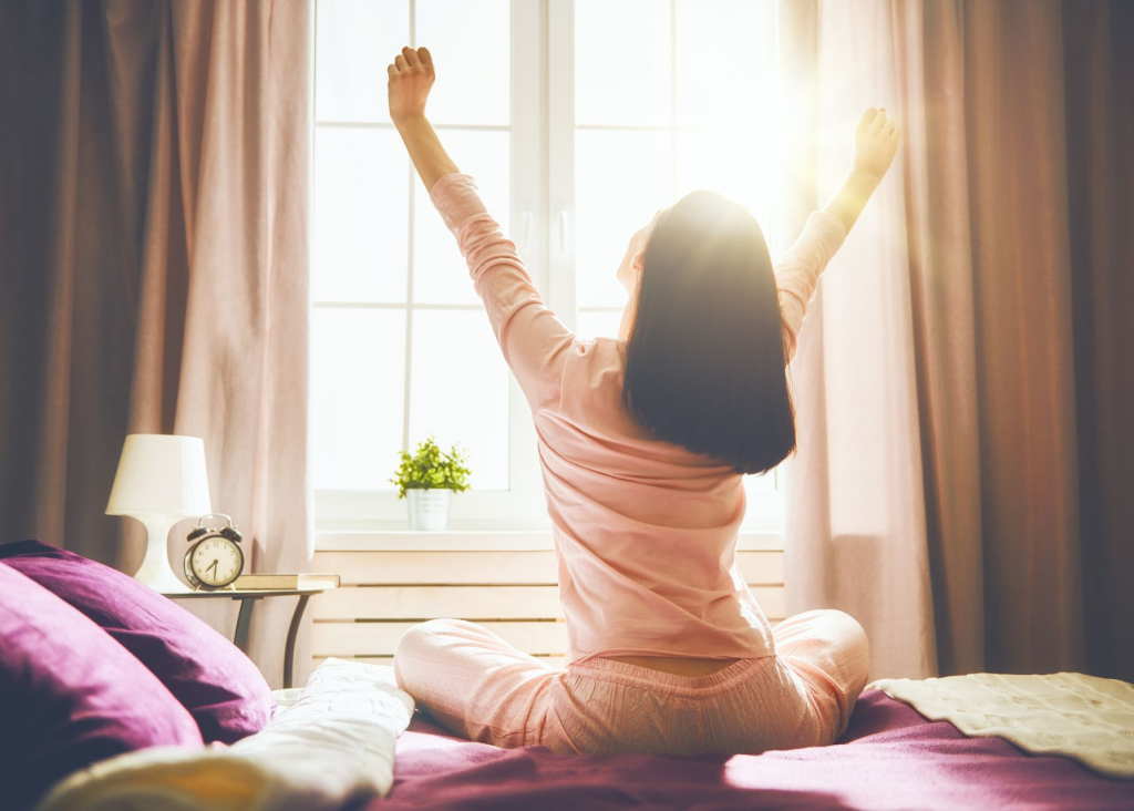 A woman enjoying the sun coming in through her window