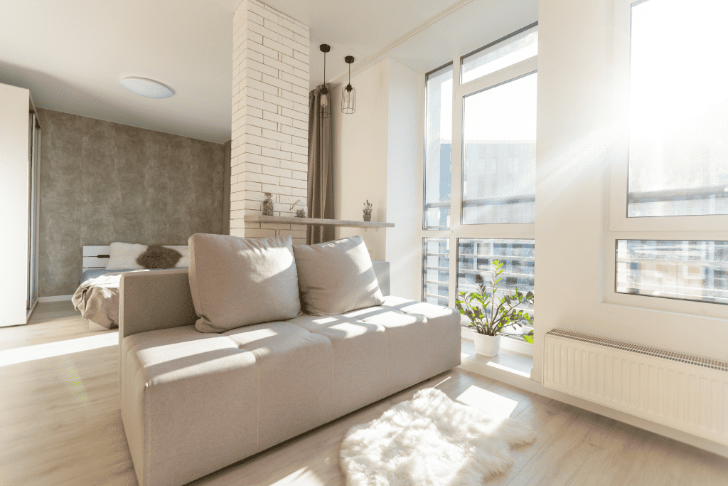  sunlight streams through a large window in a studio apartment 