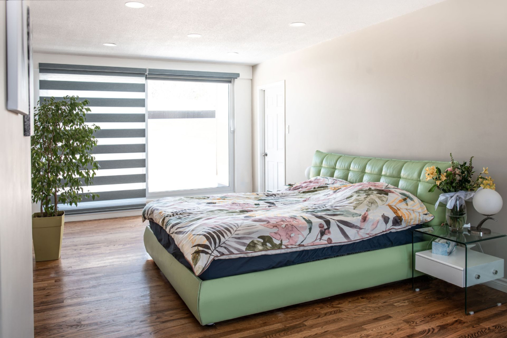 A bedroom with windows that have smart roller blinds 