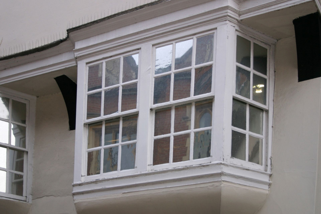 A white box bay window with grills on single-hung window panels 